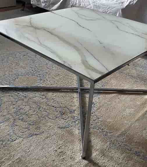 Soffbord med marmor glasskiva som en design på toppen och silver ben i metall.