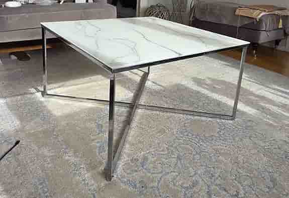 Soffbord med marmor glasskiva som en design på toppen och silver ben i metall.