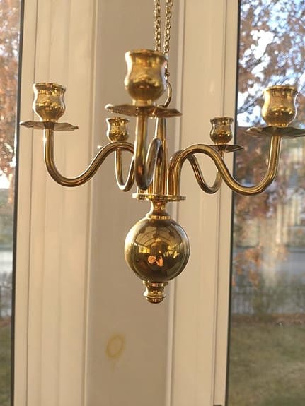 Kapellik ljuskrona i mässing hängande i en kedja.