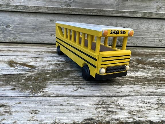 Handdekorerad skolbuss i trä – amerikansk modell med rörliga hjul