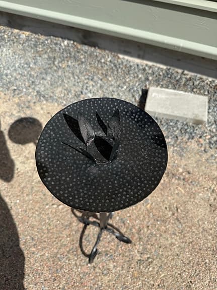 Dekorativ svart ljusstake i smide med rund ljusplatta och vackert formad fot.