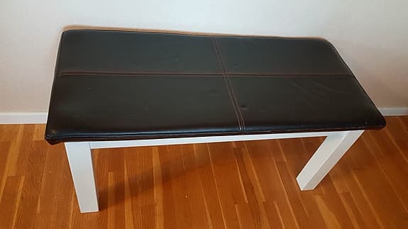Bänk med svart läderklädsel och vit ram