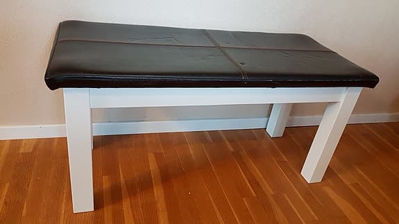 Bänk med svart läderklädsel och vit ram