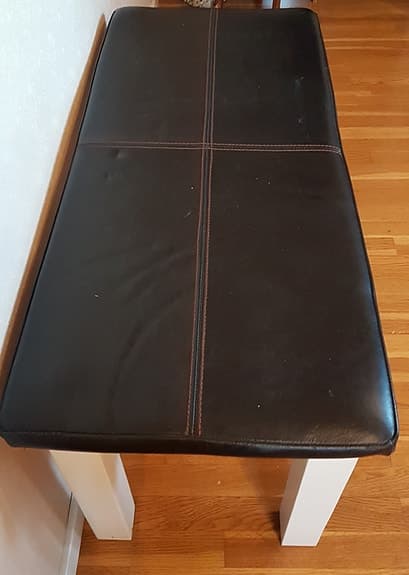 Bänk med svart läderklädsel och vit ram