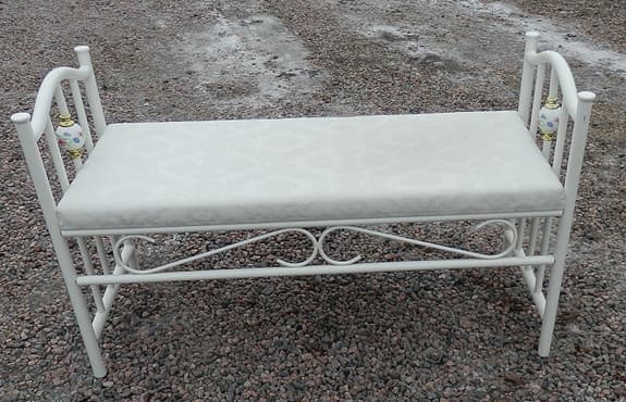 Vit bänk i metall med klädd dyna