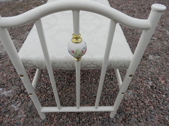 Vit bänk i metall med klädd dyna