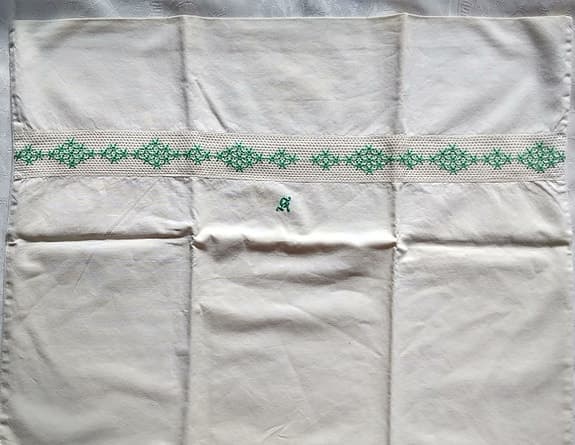 Två vita örngott med broderad bård och monogram