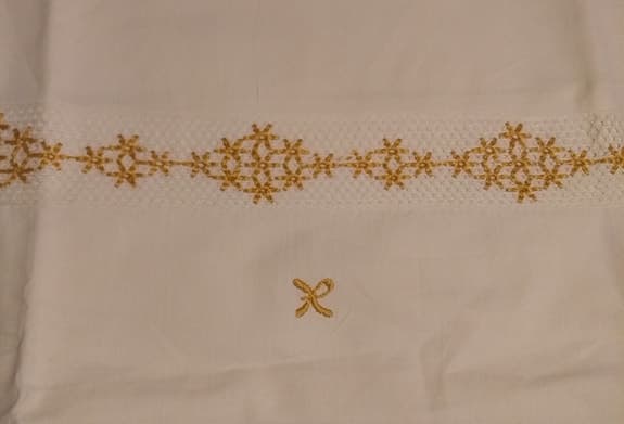 Två vita örngott med broderad bård och monogram