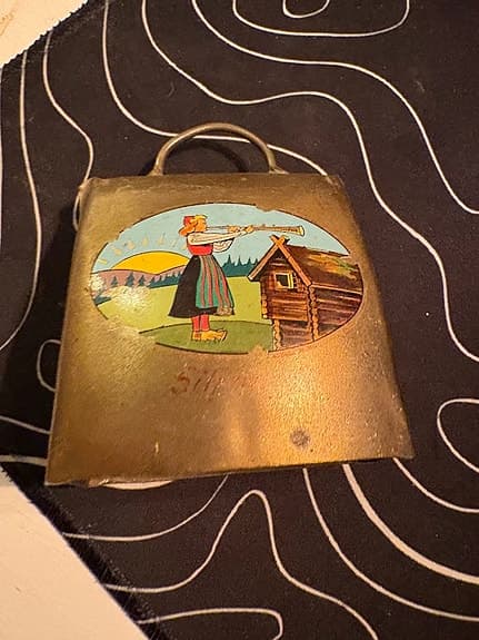 Oidentifierad Klocka i metall med handtag och dekorativ bild