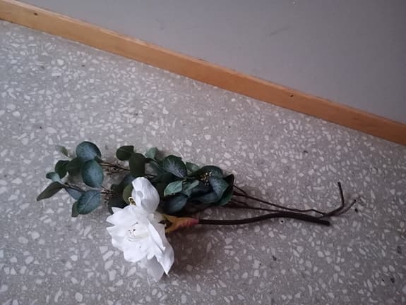 Konstgjord blomma med vit blomma och gröna blad