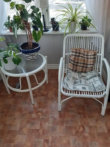 Vit rottingfåtölj med kudde och vitt rottingbord