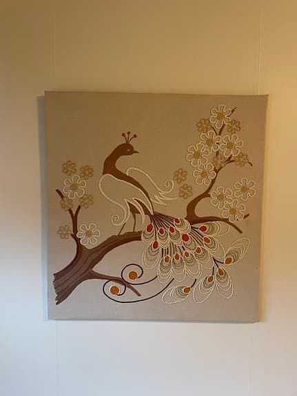 Broderad tavla med påfågelmotiv