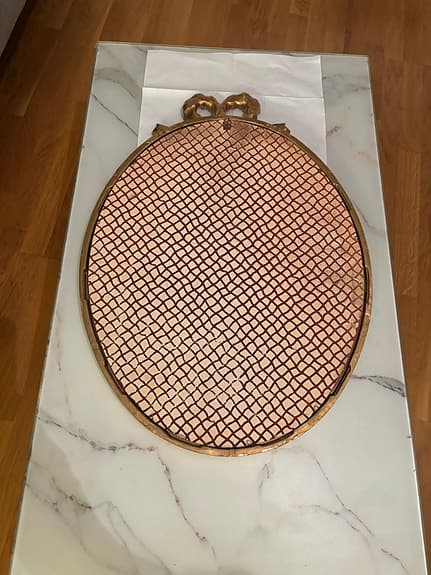 Oval spegel med guldram och dekorativ rosett