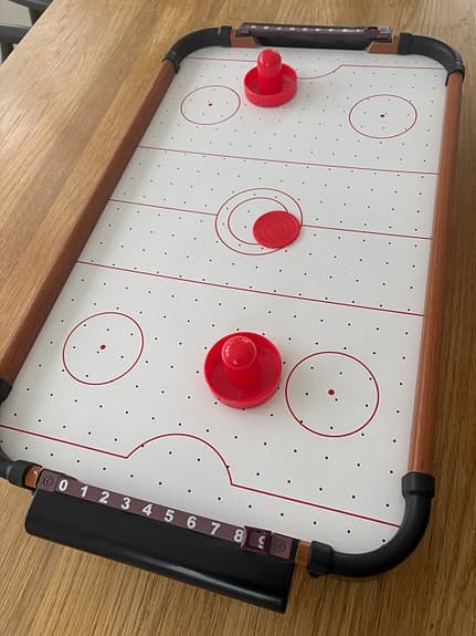 Bordsairhockeyspel med röda puckar och skyfflar