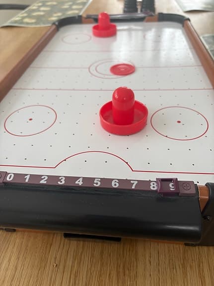 Bordsairhockeyspel med röda puckar och skyfflar