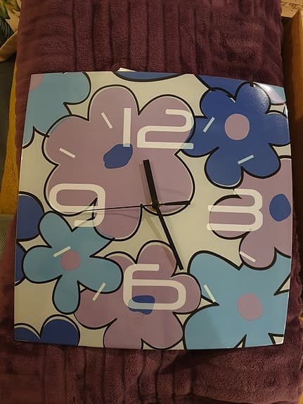 Väggklocka i glas med blommotiv