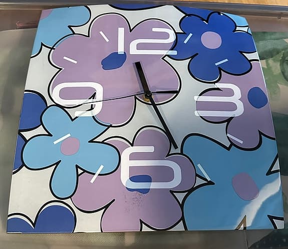 Väggklocka i glas med blommotiv