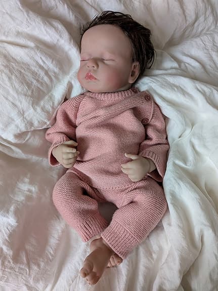 Reborn-docka med rosa stickade kläder, blöja och nappflaska