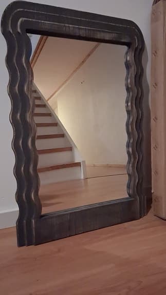 Spegel med vågig ram i mörkt trä