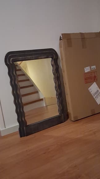 Spegel med vågig ram i mörkt trä