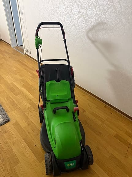 Grön elektrisk gräsklippare med uppsamlare