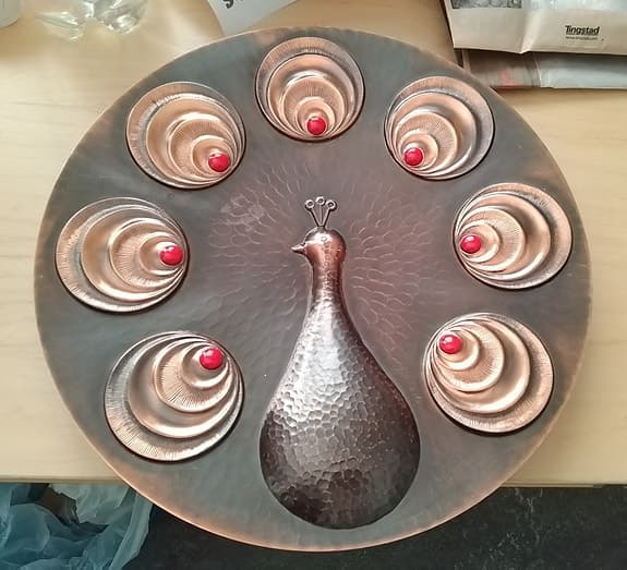 Väggdekoration i koppar med en påfågelmotiv