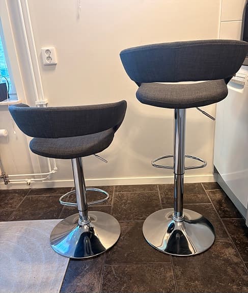 2 st tygbeklädda barstolar med sits i grått och ben i silver.