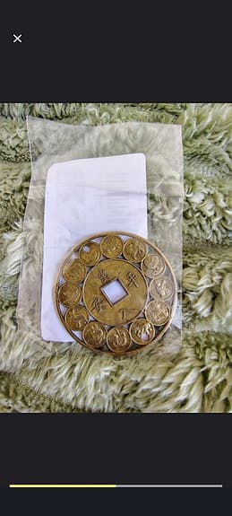 Rund metallamulett med asiatiska myntmotiv