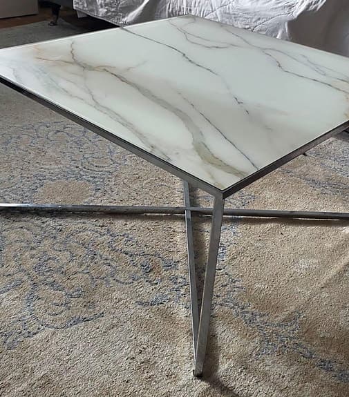 Soffbord med marmor glasskiva som en design på toppen och silver ben i metall.