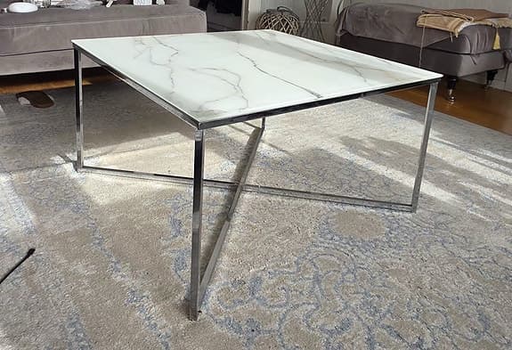 Soffbord med marmor glasskiva som en design på toppen och silver ben i metall.