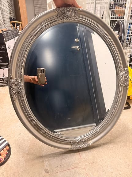 Oval spegel med dekorativ ram silverfärgad