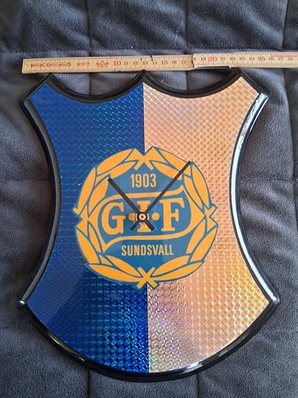 GIF Sundsvall väggklocka sköldformad blå och gul