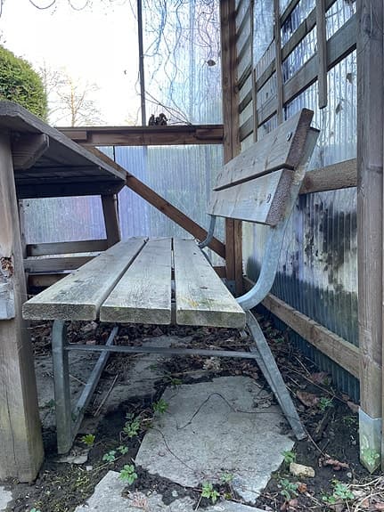 Träbänk utomhus med ryggstöd och metallstativ