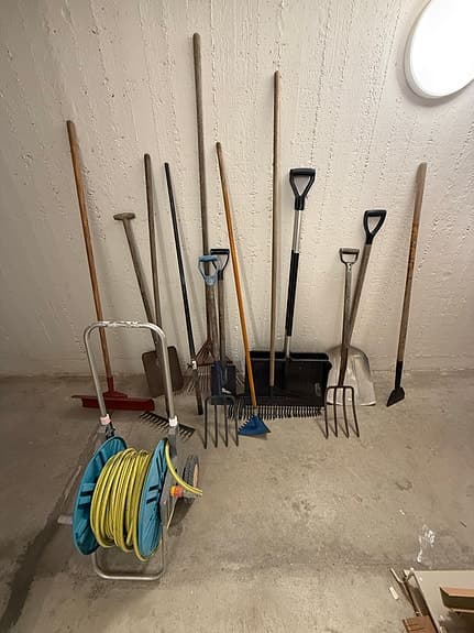 Trädgårdsredskap och vattenslang på vagn