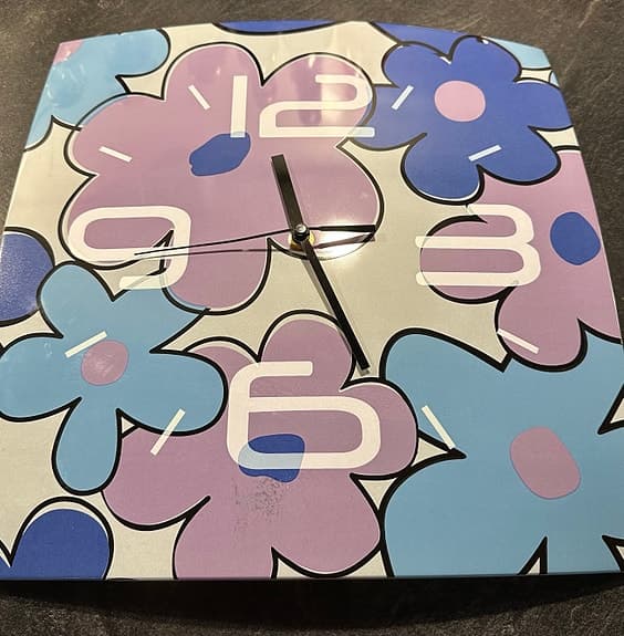 Väggklocka i glas med blommotiv