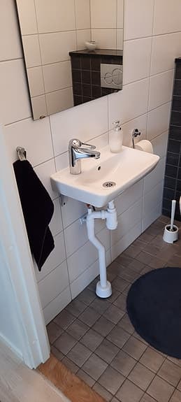Vitt handfat med blandare och spegel med ljusramp för badrum
