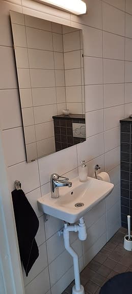 Vitt handfat med blandare och spegel med ljusramp för badrum