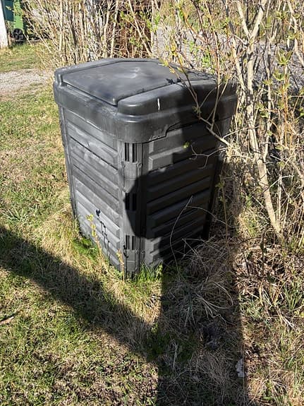 Svart kompostbehållare trädgård