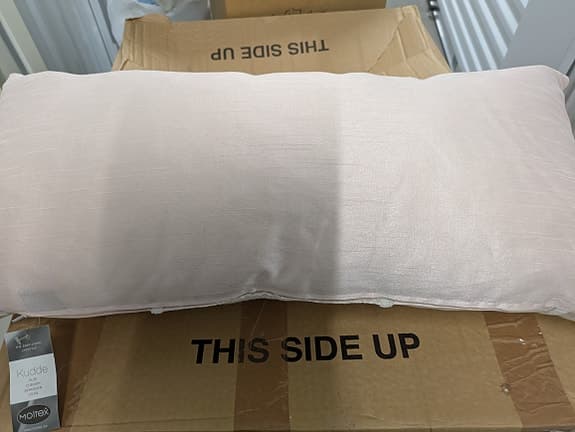 Rosa lång kudde med brokadmönster.