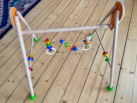 Babygym i trä med färgglada hängande leksaker