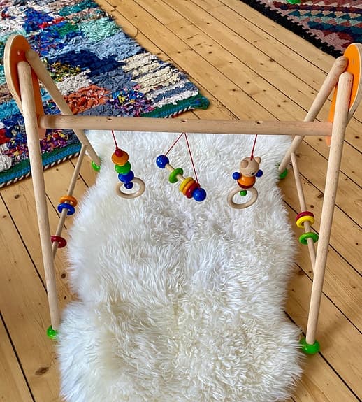 Babygym i trä med färgglada hängande leksaker