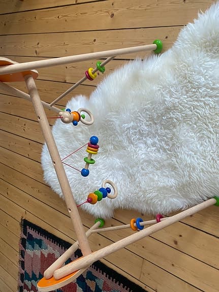Babygym i trä med färgglada hängande leksaker