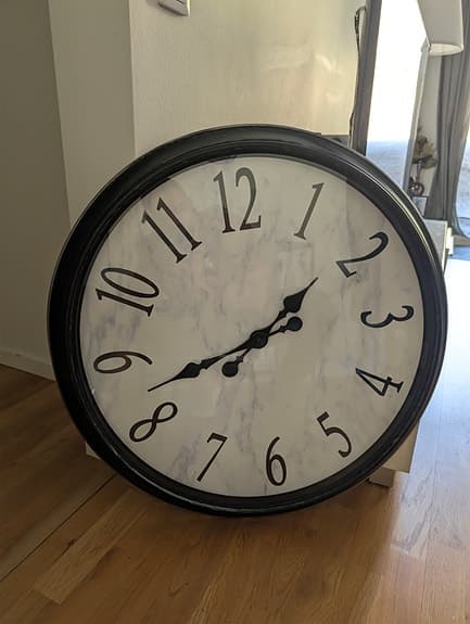 Väggklocka med grå/vit marmor bakgrund.