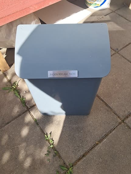 Grå postlåda i metall med lock