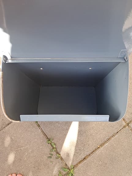 Grå postlåda i metall med lock