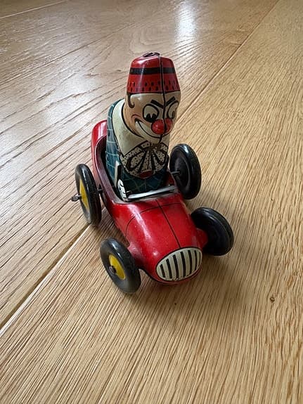 Uppdragbar plåtleksak clown i röd bil Biller
