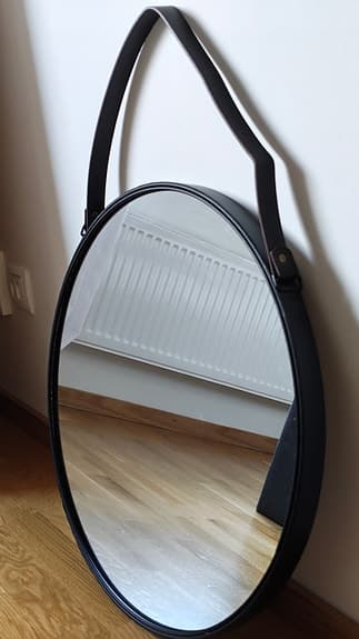 Runt spegel med svart ram och rem