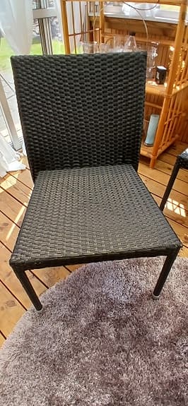 Svarta flätade utestolar i konstrotting