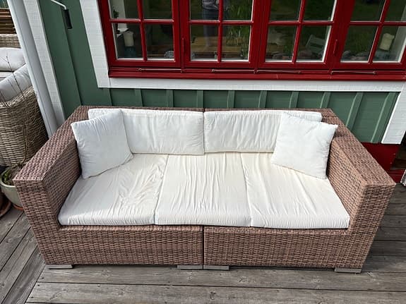 Rottingsoffa med vita dynor för uteplats