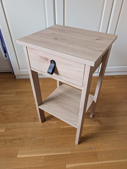 Sängbord i ljus ekdekor med läderhandtag i nyskick
